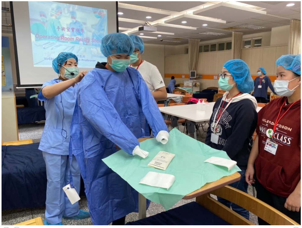 護理系彭逸稘老師在2020醫檢護理營中，指導學員穿上外科無菌手術衣帽。