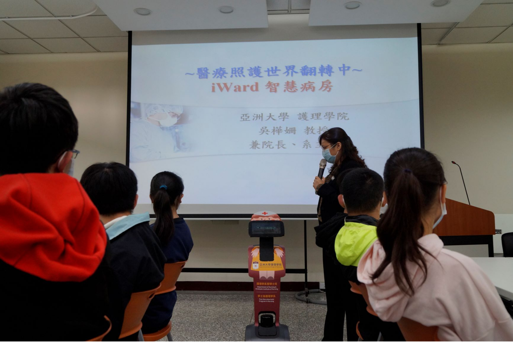 亞大「AI醫療營隊」的學員們，1月31日上午參觀護理學院，看到吳樺姍院長（站立者）與Temi照護機器人進行語音互動，都覺得十分有趣。