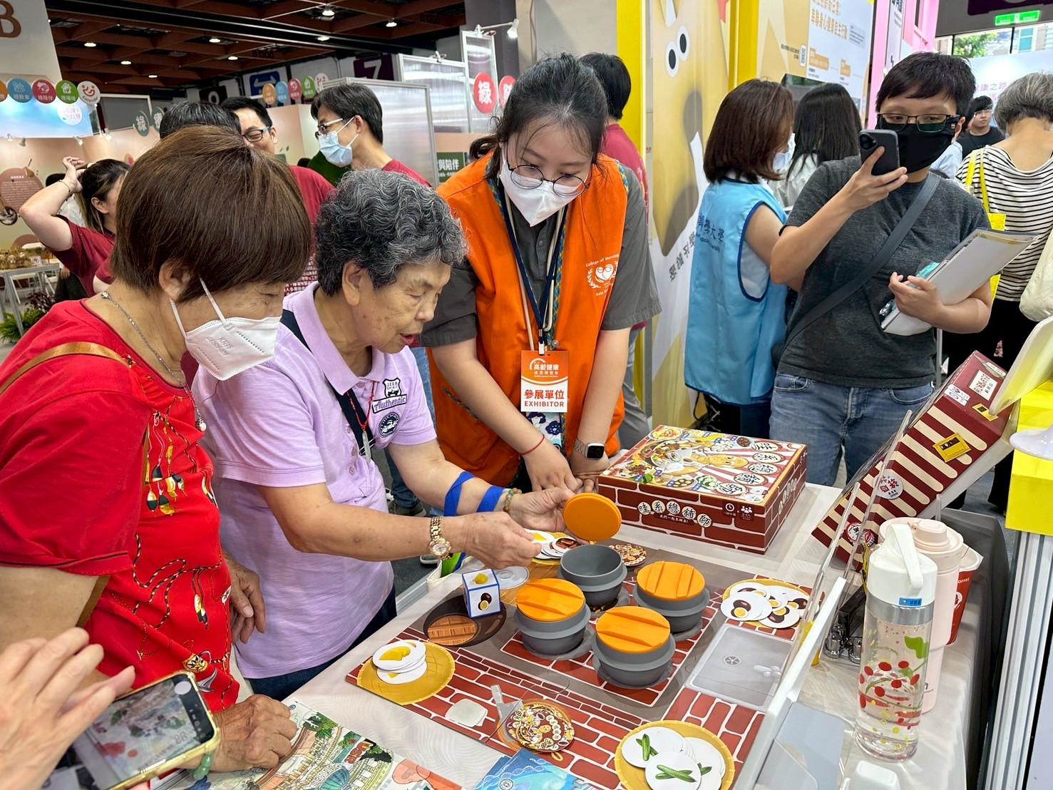 圖說：護理學院與恐龍山丘文化創意有限公司合作，將USR成果商品化為《哇系總舖師》、《阿公嬤ㄟ柑仔店》等健智桌遊，吸引許多民眾體驗、問詢。