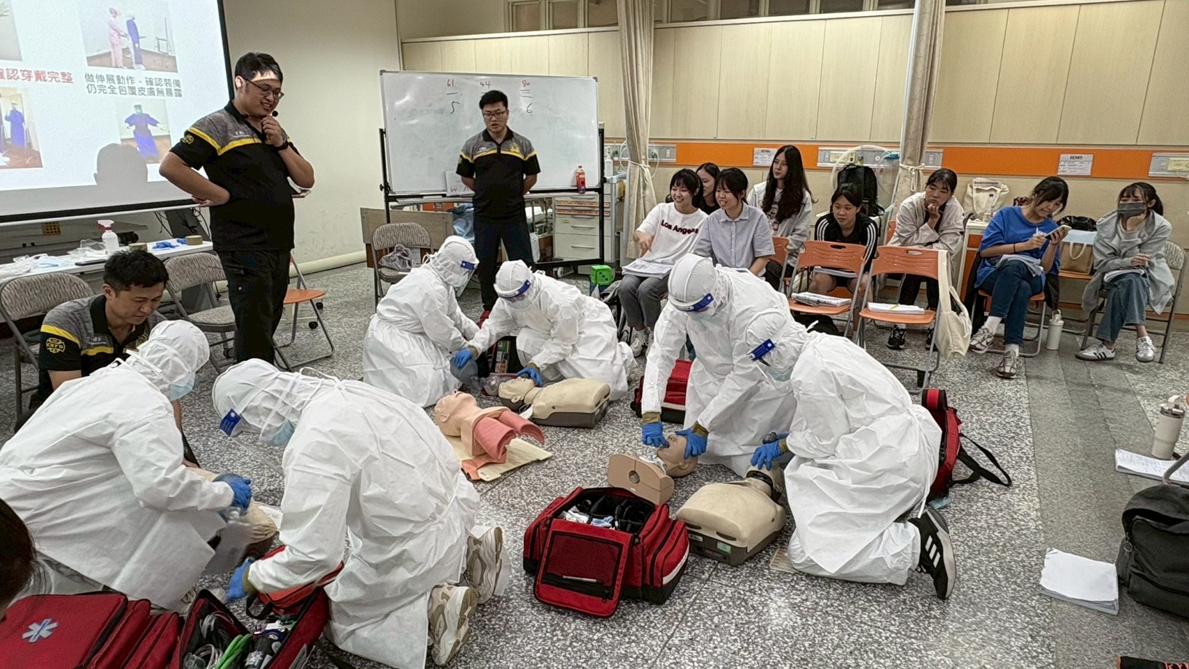 圖說：學員分組穿著標準裝備模擬演練傳染病防治流程。