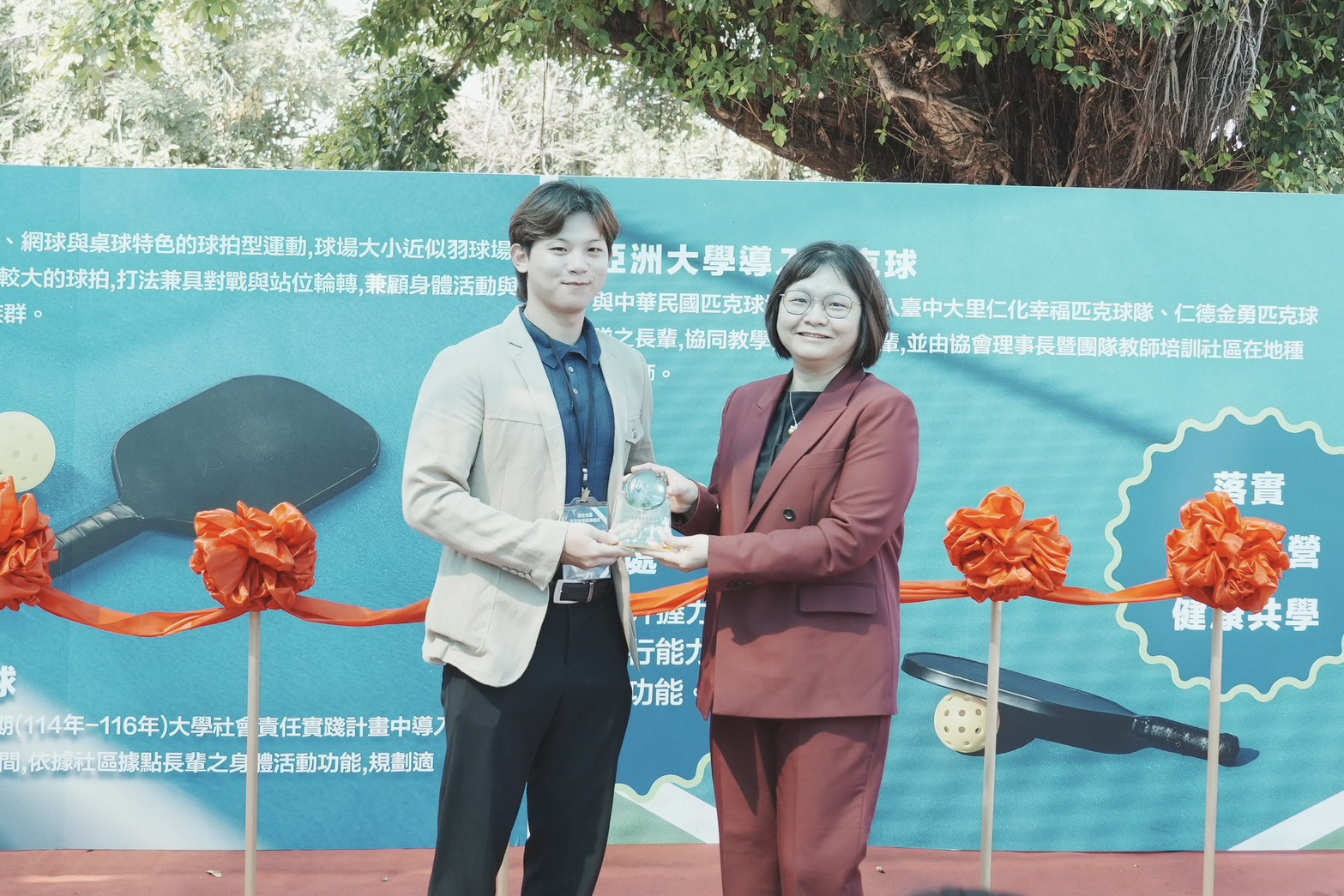 圖說：亞洲大學護理學院院長吳樺姍（右）致贈感謝獎牌予丞石運動事業有限公司主任簡克丞（左），感謝企業社會實踐支持社區發展。