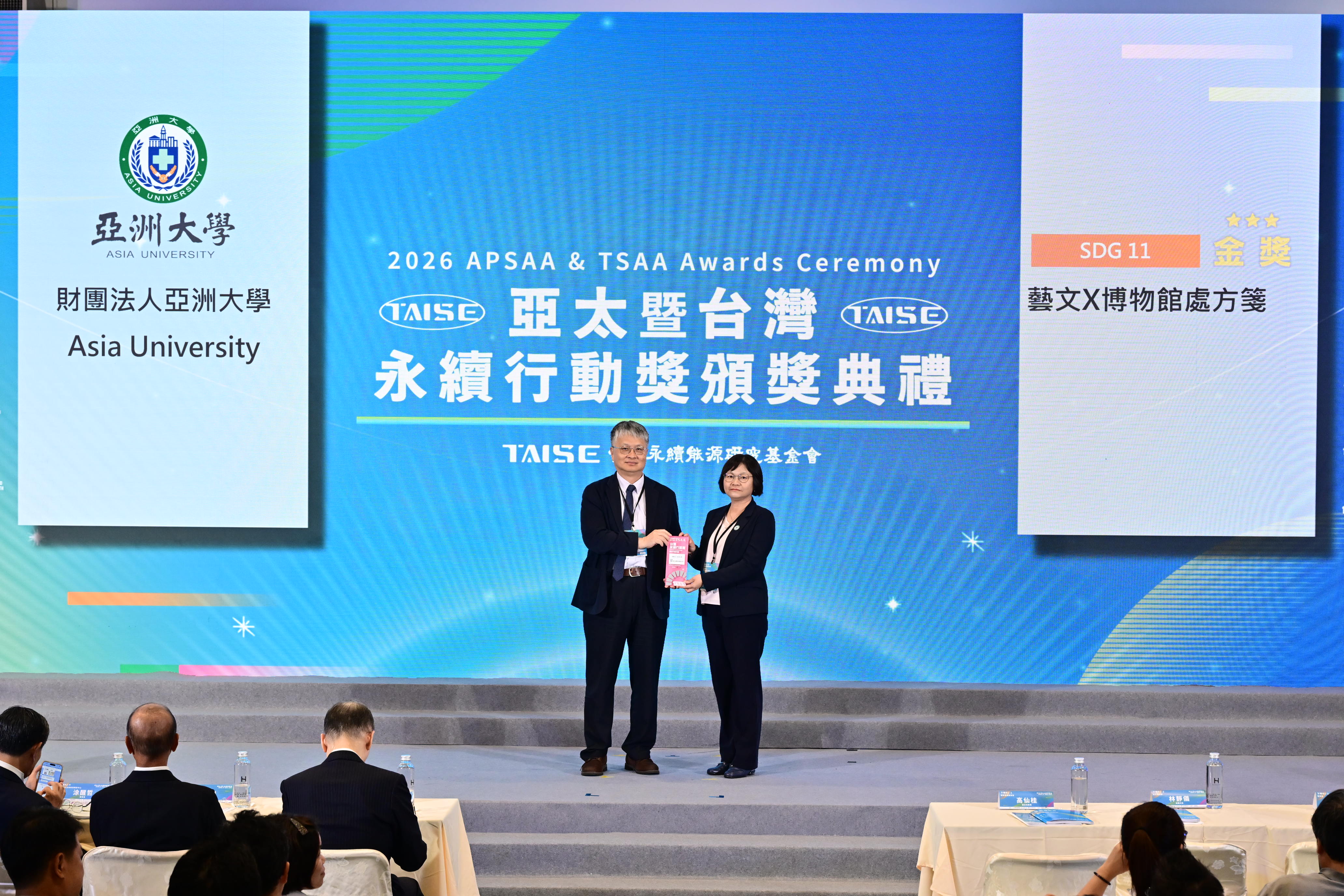 圖說：亞大護理學院USR計畫榮獲2026亞太暨台灣永續行動獎「SDG 11 永續城市－金獎」，27日由教育部政務次長劉國偉（左）頒發獎座，護理學院院長暨計畫主持人吳樺姍（右）代表出席領獎。（照片提供/台灣永續能源研究基金會）